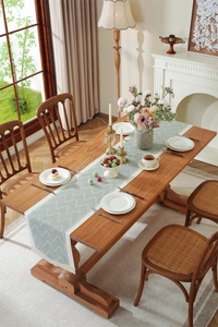 Detail of sage green geometric jacquard table runner with decorative white tassels