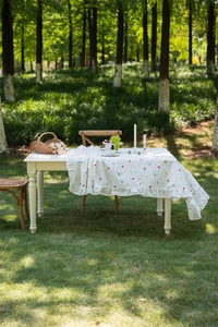 Detailed ruffled edge of a white cotton tablecloth with colorful star floral embroidery