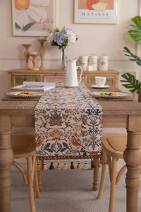 Detail of vintage floral jacquard table runner with colorful fringe tassels on wood table