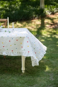French style white cotton tablecloth detail featuring colorful floral embroidery and ruffles