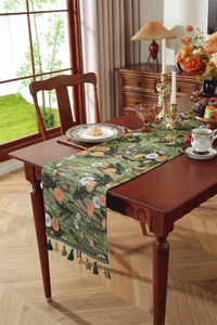 Detail of green floral table runner with orange daisies and intricate tassel fringe accents