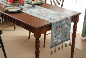 Détail du chemin de table jacquard bleu canard avec broderie classique et glands