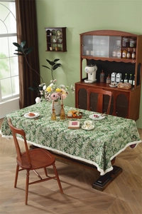 Detail of vintage dark green jacquard tablecloth with floral pattern and cream fringes