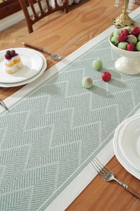 Close-up of green and white herringbone woven table runner on a wooden dining table