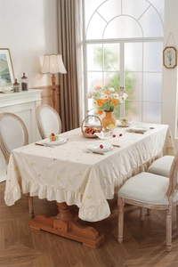 Detail of floral embroidery and ruffled edge on a premium beige cotton tablecloth