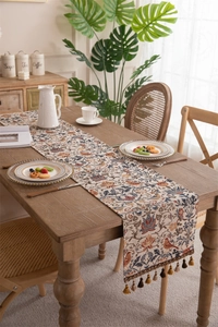 Detail of vintage floral table runner with ethnic tassels and colorful bird patterns