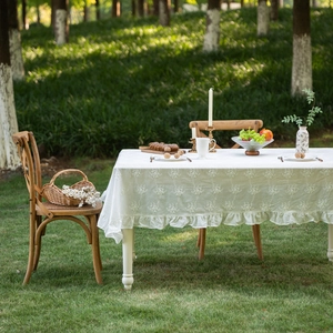French lace white embroidered cotton tablecloth with ruffled edges on outdoor table