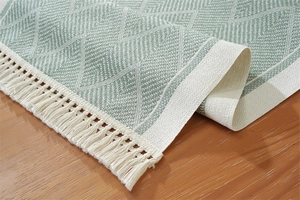 Detail of green jacquard table runner with white geometric patterns and fringe edges