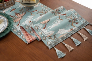 Détail du chemin de table jacquard sarcelle avec motifs de montagne et franges soyeuses