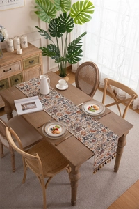 Close-up of vintage jacquard table runner with bird floral pattern and ball fringe