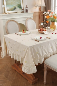 Detail of beige floral embroidered tablecloth featuring double layered ruffled edges
