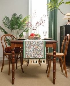 Detail of floral and bird jacquard table runner with decorative green gold tassels