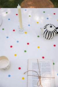 Detail of white cotton tablecloth featuring colorful floral embroidery and ruffled edges