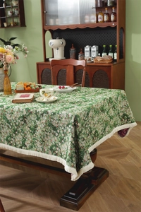 Detail of green floral jacquard tablecloth with white tassel edge and vintage texture
