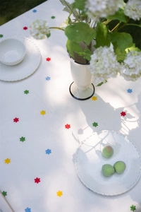 Close-up of French cotton tablecloth with colorful floral embroidery and ruffled edge texture