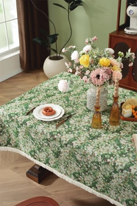 Close-up of green floral tablecloth with oil painting texture and elegant white tassels
