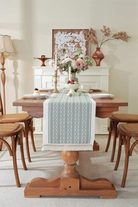 Close-up of bohemian green geometric jacquard table runner with decorative white tassels
