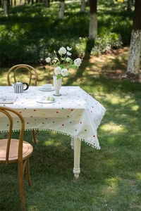 Close-up of colorful floral embroidery and white pom-pom trim on French cotton tablecloth