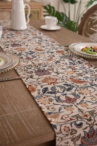 Close-up of vintage table runner with colorful floral bird patterns and tassel details