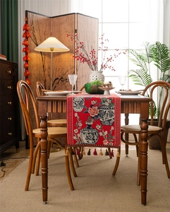 Détail du chemin de table rouge avec motif de vase floral et pompons décoratifs élégants