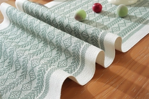 Close-up of woven table runner featuring green geometric leaf patterns and texture