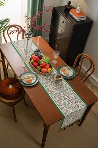 Detail of vintage floral table runner with intricate tassels and red flower patterns