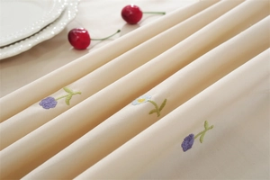 Detailed embroidery on apricot cotton tablecloth with floral patterns and ruffled edge