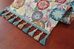 Detail of bohemian jacquard table runner with vintage floral patterns and tassels