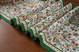 Detailed close-up of retro floral and bird jacquard table runner with green borders