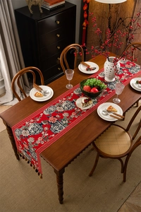 Détail du chemin de table jacquard rouge avec pivoines, porcelaine et bords à glands