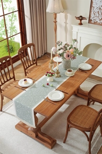 Detail of sage green jacquard table runner with decorative fringe tassels and fabric texture
