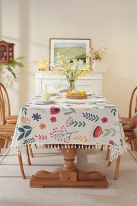 Detail of Easter floral tablecloth featuring fringe edges on a rustic wooden dining table
