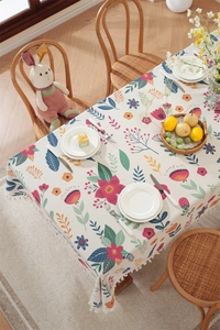 Close-up of Easter floral tablecloth with white tassels on a cozy wooden dining table