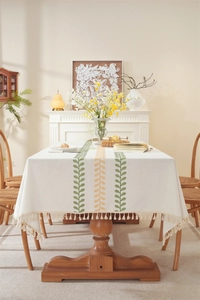 Detailed embroidery of green coffee leaves and beige tassels on rectangular tablecloth