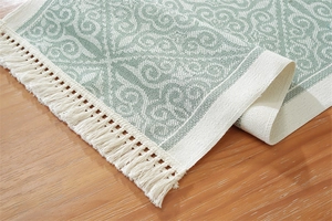 Close-up of sage green and cream jacquard table runner with decorative white fringe