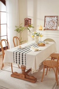 Close-up of linen table runner with bohemian black stripes and tassel details