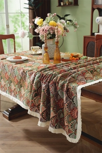 Close-up of vintage jacquard tablecloth featuring intricate patterns and white fringe tassels