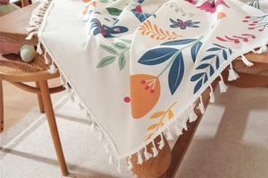 Close-up of floral Easter tablecloth with cotton tassels on a rustic wooden table