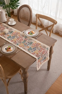 Detail of floral jacquard table runner with tassels on a dark wood dining table