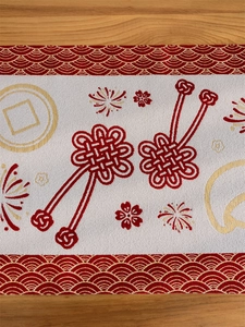 Close-up of red and beige table runner with woven Chinese knots and floral patterns