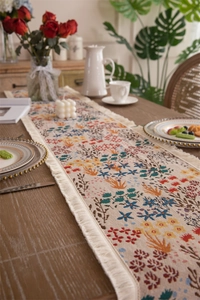 Detailed texture of jacquard floral table runner with elegant white fringe tassels