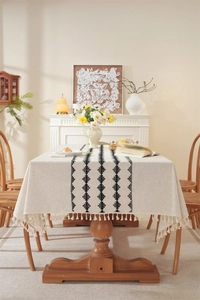 Close-up of linen table runner with black geometric diamond pattern and white tassels