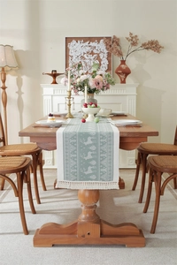 Macro detail of green jacquard table runner with moose patterns and decorative tassels