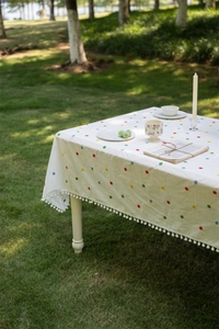 Detailed view of floral embroidery and pom-pom tassel edge on French cotton tablecloth