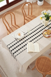 Detailed view of beige cotton linen table runner with black geometric patterns and tassels