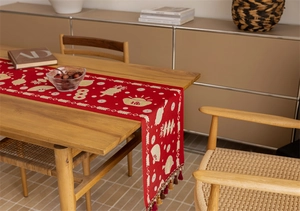 Detailed close-up of red festive table runner with golden patterns and colorful tassels
