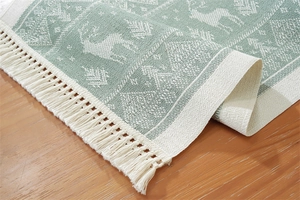 Close-up of woven table runner featuring sage green reindeer jacquard and tassel edge