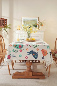 Detail of Easter tablecloth featuring floral rabbit print and decorative pompom tassels