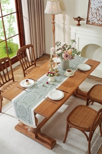 Detailed close-up of a vintage sage green jacquard table runner with white floral patterns