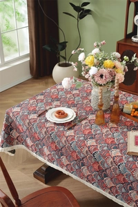 Close-up of vintage red and blue jacquard tablecloth with delicate white tassel fringe detail